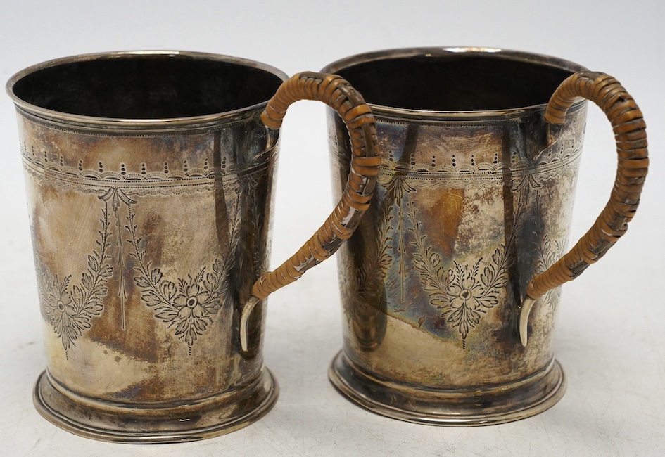 A pair of George V engraved silver mugs, with rattan handles, William Aitken, Birmingham, 1920, height 95mm, gross weight 5.9oz. Condition - fair